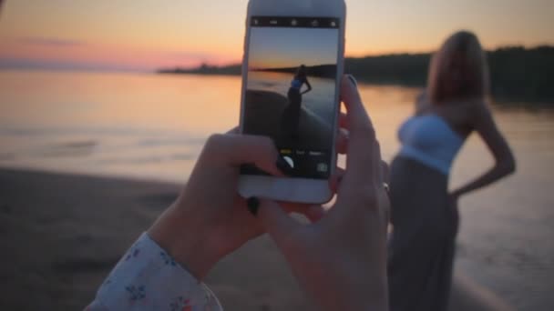 取っている女の子の写真が携帯電話に彼女の妊娠中のガール フレンド夕日 — ストック動画