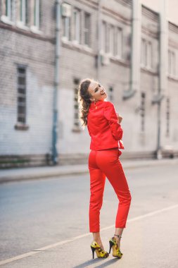 Gülümseyen ve kırmızı elbiseli güneşli bir günde poz bir güzel parlak kız sokak stili yaşam portresi