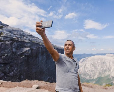 Norveç, selfie, özgürlük elinde tutan bir smartphone dağlar kjeragbolten kjerag taştan yakışıklı yaşlı adam için bir aşırı planı seyahat portresi