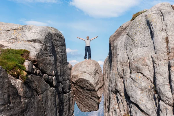 Portrait of a extreme plan travel for the handsome old man on the stone of the kjerag in the mountains kjeragbolten of Norway,   selfie on a smartphone holding in your freedom hand