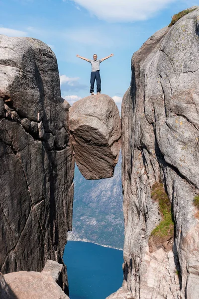 Portrait of a extreme plan travel for the handsome old man on the stone of the kjerag in the mountains kjeragbolten of Norway,   selfie on a smartphone holding in your freedom hand