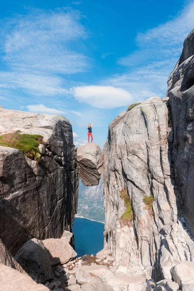 Portrait of a extreme plan travel for the girl on the stone of the kjerag in the mountains kjeragbolten of Norway, the feeling of complete freedom