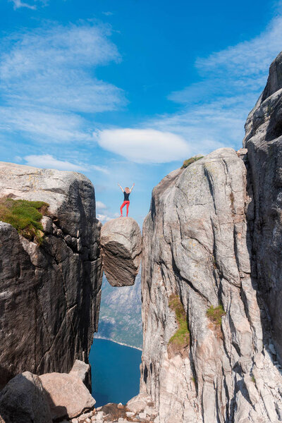 Портрет экстремального плана путешествия для девушки на камне кьярага в горах Кьярагболтена Норвегии, ощущение полной свободы
 
