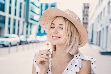 Portre güzel poz ve sokak yaşam tarzı üzerinde gülümseyen güneşli günde dolgun dudaklar ile modern şapkalı'deki genç sarışın kız 