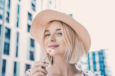 Portre güzel poz ve sokak yaşam tarzı üzerinde gülümseyen güneşli günde dolgun dudaklar ile modern şapkalı'deki genç sarışın kız 