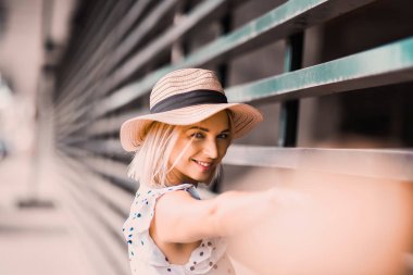 Portre güzel poz ve sokak yaşam tarzı üzerinde gülümseyen güneşli günde dolgun dudaklar ile modern şapkalı'deki genç sarışın kız 
