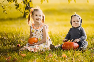 yakın çekim portre romantik turuncu şirin elbise ve çocuk ile ejderha kostümlü bir sarı sonbahar Bahçe park güneşli gün gülümseyerek Halloween pumpkins ile kutluyor içinde güzel bir kız