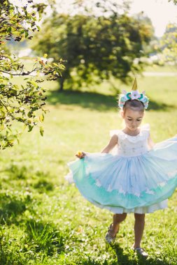 bir romantik mavi elbiseli şirin ile Bahçe park güneşli gün gülümseyerek unicorn ile Cadılar Bayramı kutlamak bir yeşil sonbaharda güzel bir kızın yakın çekim portre