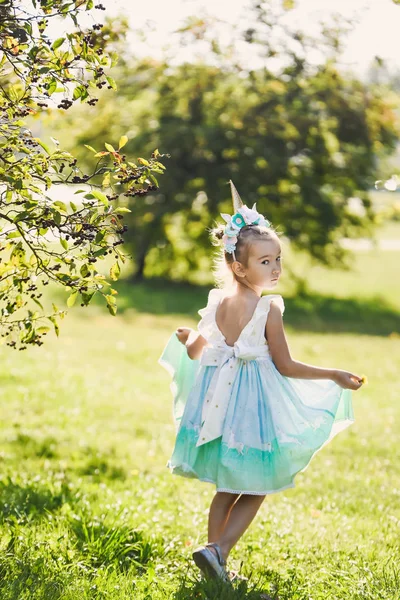 特写肖像一个美丽的女孩在浪漫的蓝色可爱的礼服与在一个绿色的秋季花园公园微笑阳光明媚的一天庆祝万圣节与独角兽 — 图库照片