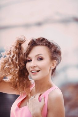 yakın çekim yaşam tarzı bir sokakta gülümseyen güneşli bir günde bir pembe tüy elbiseli kıvırcık saçlı Genç güzel seksi kız portresi