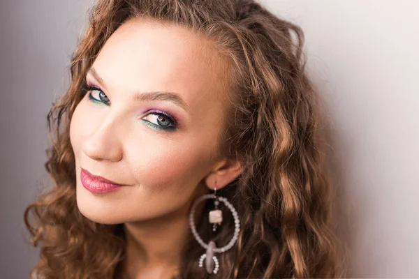 portre profesyonel makyaj ve açık diş gülümseme pembe ruh hali ile stüdyoda poz güzel sarışın kıvırcık kız