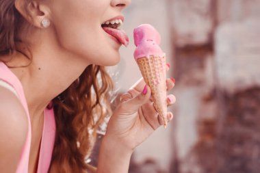 yakın çekim bir gözleme dondurma boynuz yalıyor tutan pembe elbise ve yaşam tarzı gülümseyen puffs kıvırcık saçlı Genç güzel seksi kız portresi