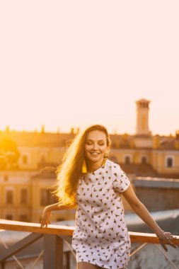 turuncu günbatımı bir arka plan üzerinde beyaz kısa yaz elbisesi güzel bir genç seksi kız gülümseme dişleri portresi