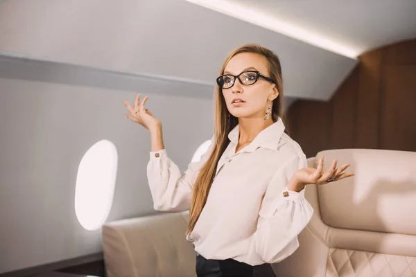 beautiful young girl in the cabin of a business class airplane with a phone in her hands comfortable luxury travel close to the porthole