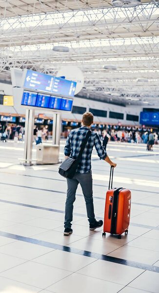 Европейский ботаник из аэропорта в очках и клетчатой рубашке с багажным туристическим самолетом, летящим в маске для лица. Вирусы коронавируса гриппа 