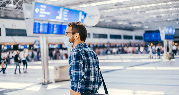 Европейский ботаник из аэропорта в очках и клетчатой рубашке с багажным туристическим самолетом, летящим в маске для лица. Вирусы коронавируса гриппа 