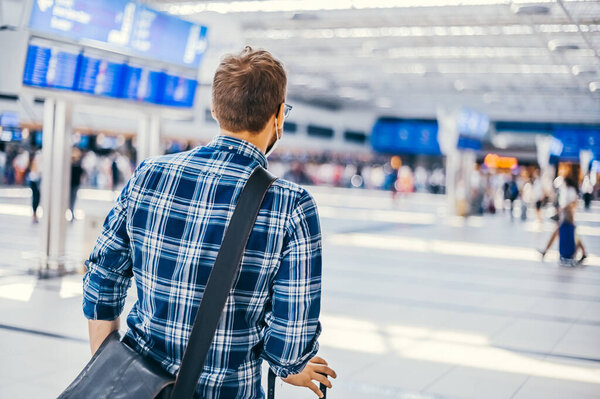 Европейский ботаник из аэропорта в очках и клетчатой рубашке с багажным туристическим самолетом, летящим в маске для лица. Вирусы коронавируса гриппа 