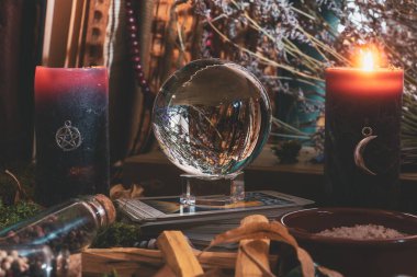 Kristal küre, tarot kartları, mumlar, şifalı bitkiler ve kehanet ve ayin için kullanılan sihirli aletlerle sunak sahnesi..