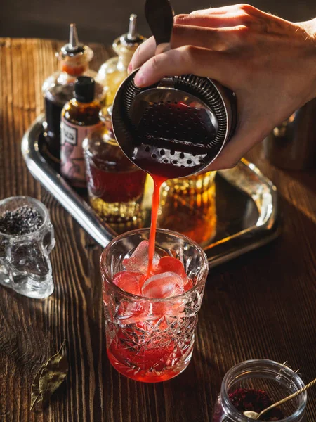 Bir kırmızı bir barda bir bardak dökme kokteyl kokteyl dikey yapma barmen yakın çekim
