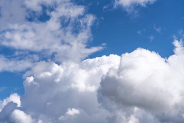 Açık mavi gökyüzünde parlak kümülüs bulutları. Kabarık beyaz oluşumlara sahip atmosferik bulutlar, hava, iklim, saflık sembolü, yaz günü ve gökyüzü ve atmosfer kavramları için doğal arka plan.
