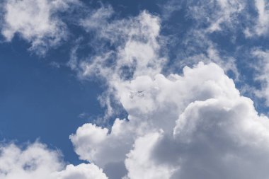 Mavi gökyüzünde kümülüs bulutları arasında uçan yolcu uçağı. Seyahat, havacılık, ulaşım, özgürlük, hava trafiği, iklim değişikliği ve bulutlu ve uçaklı atmosfer manzarası kavramı.