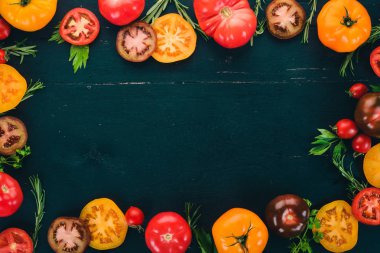 Ürün yelpazesine renkli taze domates. Siyah ahşap arka plan üzerinde. Üstten Görünüm. Kopya alanı.