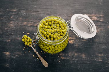 Bir kavanoz turşu yeşil bezelye. Gıda stokları. Üstten Görünüm. Ahşap bir arka plan üzerinde. Kopya alanı.