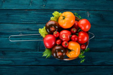 Taze domates metal sepet içinde. Ahşap bir arka plan üzerinde. Üstten Görünüm. Kopya alanı.