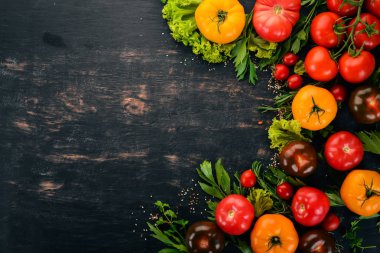 Ürün yelpazesine renkli taze domates. Siyah ahşap arka plan üzerinde. Üstten Görünüm. Kopya alanı.