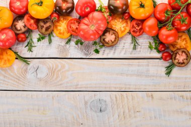 Beyaz ahşap arka plan üzerinde renkli domates. Üstten Görünüm. Kopya alanı.