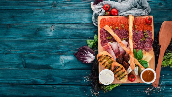 Meat cut and cold snacks. Italian cuisine. On a wooden background. Top view. Copy space.