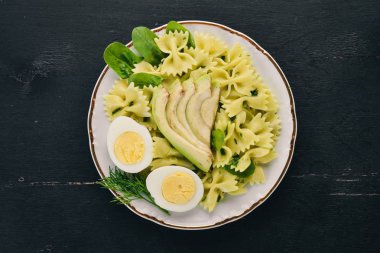 Makarna ıspanak, avokado ve haşlanmış yumurta. Ahşap bir arka plan üzerinde. Üstten görünüm. Kopya alanı.