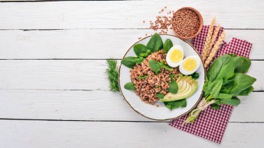 Karabuğday avokado, ıspanak ve haşlanmış yumurta. Ahşap bir arka plan üzerinde. Üstten görünüm. Kopya alanı.