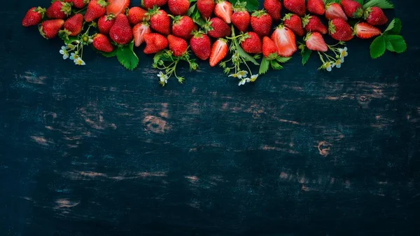 Fresh strawberries. On a black wooden background. Top view. Copy space.