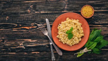 Bulgur bir plaka üzerinde Fesleğenli. Ahşap bir arka plan üzerinde. Üstten görünüm. Kopya alanı.