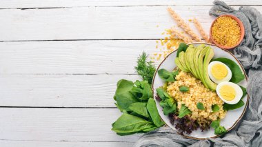 Bulgur avokado, ıspanak ve haşlanmış yumurta. Ahşap bir arka plan üzerinde. Üstten görünüm. Kopya alanı.