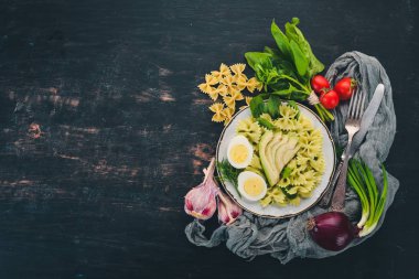Makarna ıspanak, avokado ve haşlanmış yumurta. Ahşap bir arka plan üzerinde. Üstten görünüm. Kopya alanı.