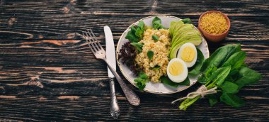 Bulgur avokado, ıspanak ve haşlanmış yumurta. Ahşap bir arka plan üzerinde. Üstten görünüm. Kopya alanı.