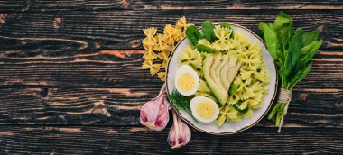 Makarna ıspanak, avokado ve haşlanmış yumurta. Ahşap bir arka plan üzerinde. Üstten görünüm. Kopya alanı.