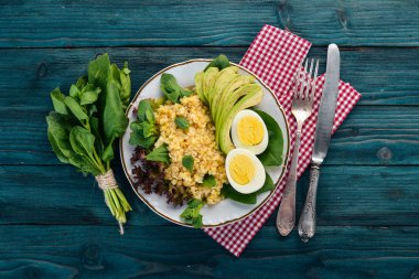 Bulgur avokado, ıspanak ve haşlanmış yumurta. Ahşap bir arka plan üzerinde. Üstten görünüm. Kopya alanı.
