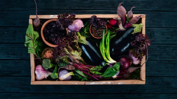Purple food. Fresh vegetables and berries in a wooden box. On a wooden background. Top view. Copy space.