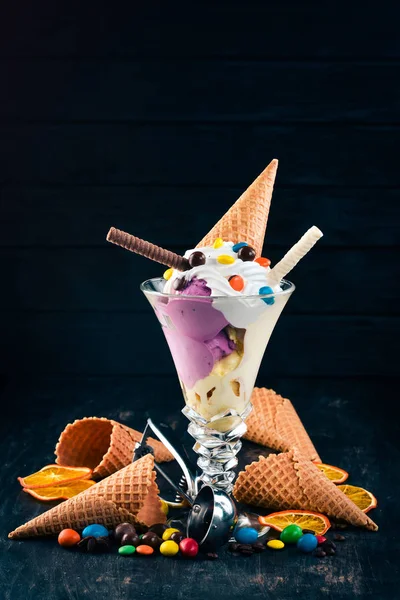 Vanilla ice cream with colored candies. On a black wooden background. Copy space.