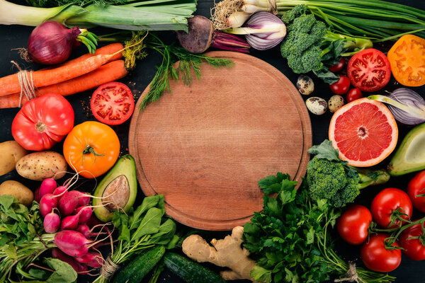 Здоровое питание. Овощи и фрукты. На черном деревянном фоне. Вид сверху. Копирование пространства.