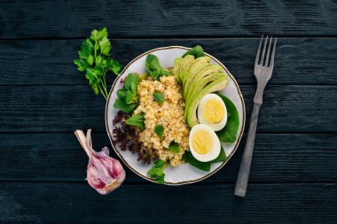 Bulgur avokado, ıspanak ve haşlanmış yumurta. Ahşap bir arka plan üzerinde. Üstten görünüm. Kopya alanı.