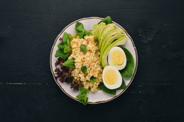 Bulgur avokado, ıspanak ve haşlanmış yumurta. Ahşap bir arka plan üzerinde. Üstten görünüm. Kopya alanı.