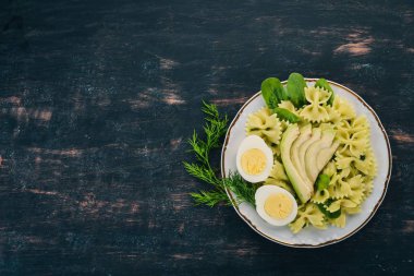 Makarna ıspanak, avokado ve haşlanmış yumurta. Ahşap bir arka plan üzerinde. Üstten görünüm. Kopya alanı.