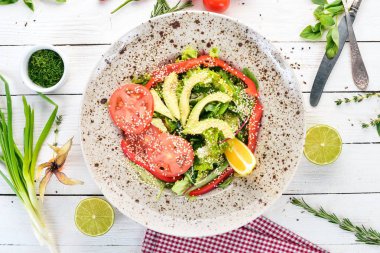 Avokado, domates, taze sebze salatası. Ahşap bir arka plan üzerinde. Üstten görünüm. Kopya alanı.