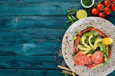 Avokado, domates, taze sebze salatası. Ahşap bir arka plan üzerinde. Üstten görünüm. Kopya alanı.