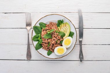 Karabuğday avokado, ıspanak ve haşlanmış yumurta. Ahşap bir arka plan üzerinde. Üstten görünüm. Kopya alanı.