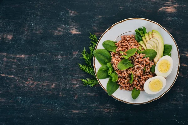 Karabuğday avokado, ıspanak ve haşlanmış yumurta. Ahşap bir arka plan üzerinde. Üstten görünüm. Kopya alanı.